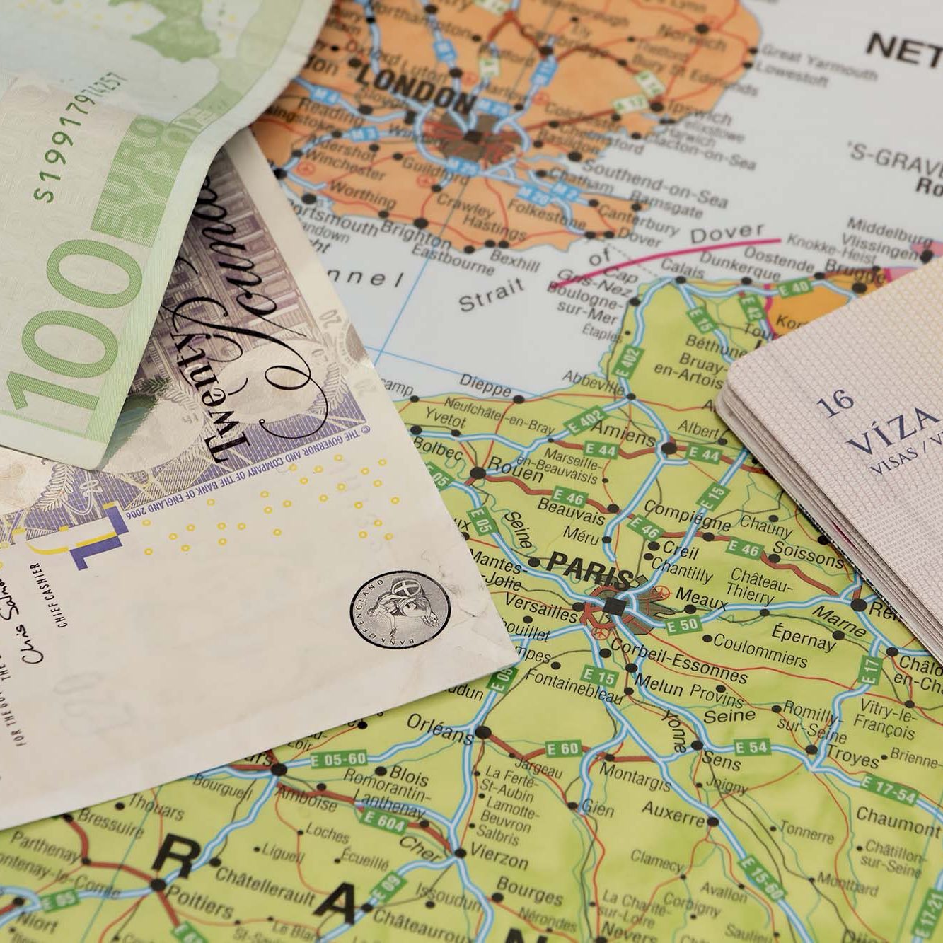 Passport and money sitting on a map showing Paris & London